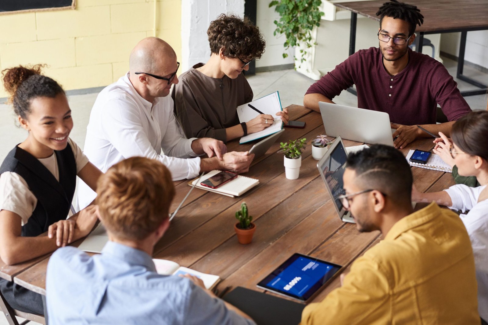 Diverse professionals meeting around a wooden table — Photo by fauxels on Pexels